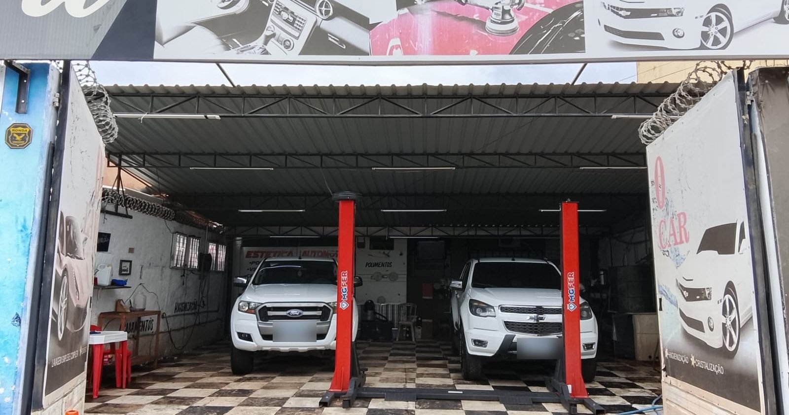 Fachada da Top10 Lava Car: espaço coberto com dois elevadores e caminhonetes em atendimento